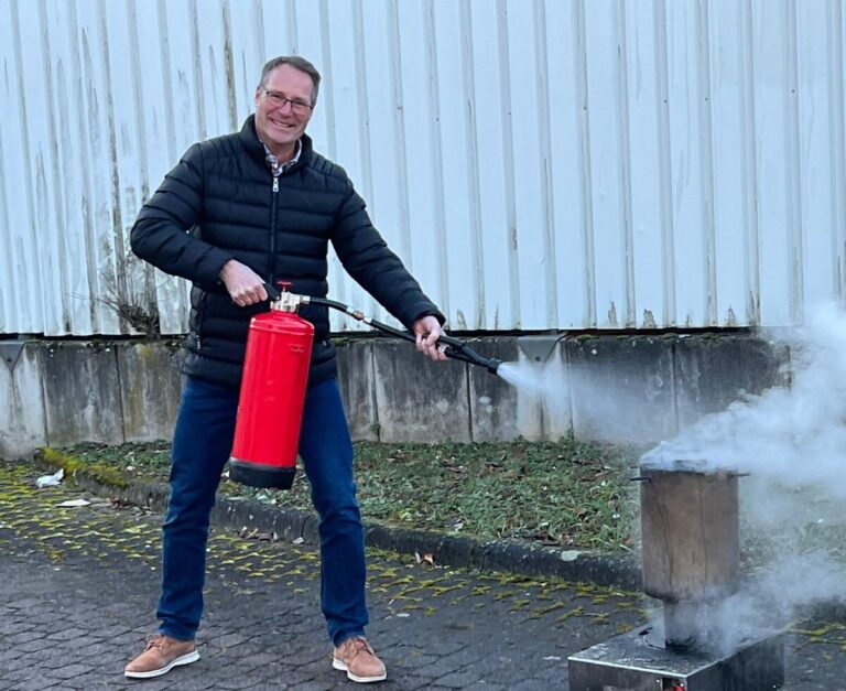 Mitarbeiter von One IT benutzt einen Feuerlöscher während einer Sicherheitsübung im Freien.